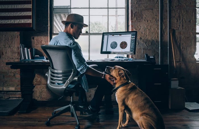 Un homme qui travaille sur un ordinateur avec son chien 