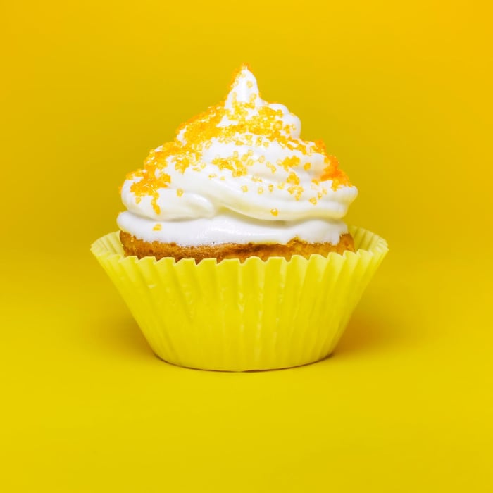 Cupcake with white topping and yellow sprinkles.