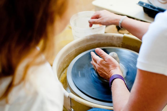 Person making clay pottery on a turning table