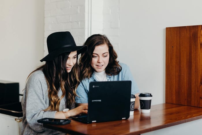 Dwie kobiety przed ekranem laptopa, pracujące przez internet.