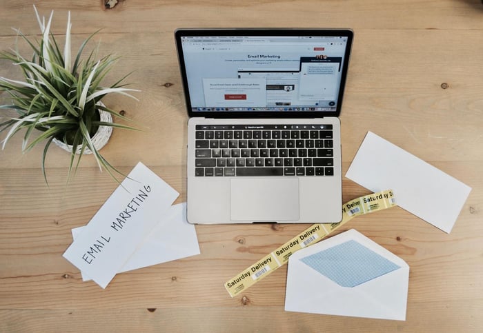 Email marketing no notebook, papeis e planta sobre uma mesa