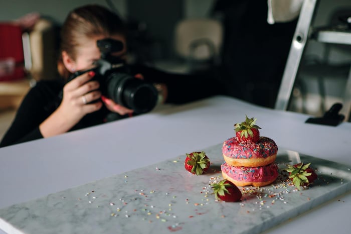 Girl taking a photo of cakes inside