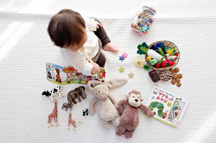 Un niño sentado sobre una manta blanca con juguetes