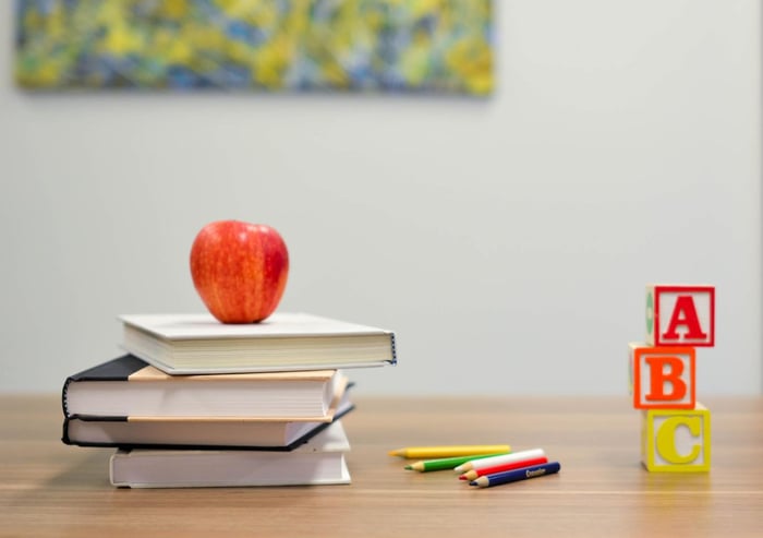 Livres, crayons, une pomme et des blocs abc sur une table 