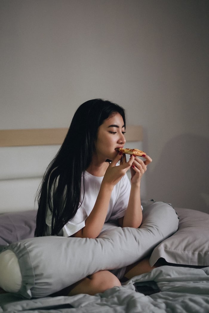 mujer comiendo pizza en la cama