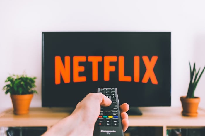 pessoa apontando controle remoto para o logotipo da Netflix na tela da TV
