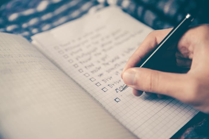 Seseorang menulis checklist ide bisnis di buku catatan