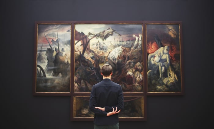 uomo che fissa grandi opere d'arte sul muro della galleria