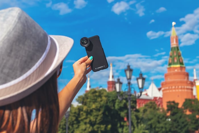Wanita mengambil selfie dengan lensa tambahan untuk kamera ponsel