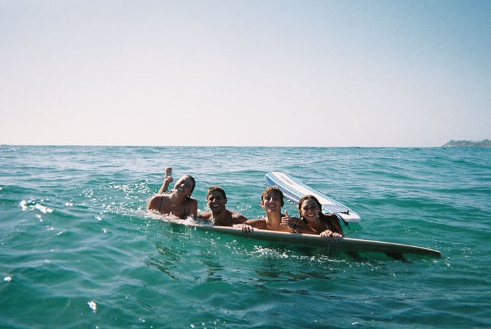 People smiling on a surf board in water 