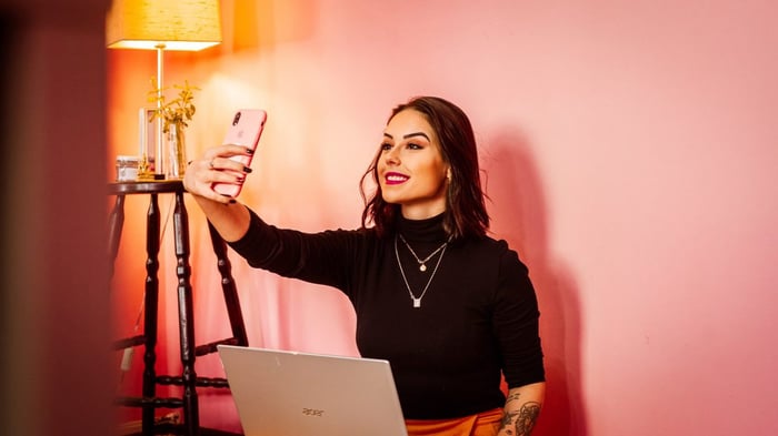 A person taking a selfie against a pink wall