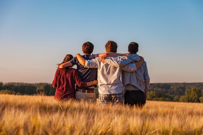 A group of friends in a field against a blue sky
