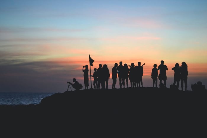 Group of people together at a cliff side at sunrise