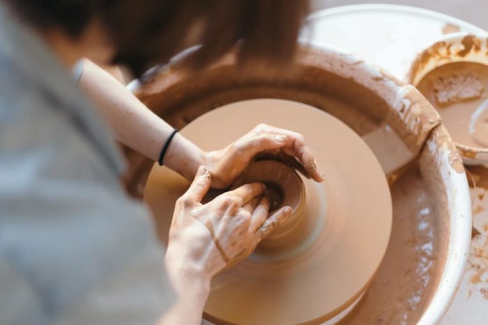 Cerâmicas e vasos sendo feitos feitos à mão por uma pessoa