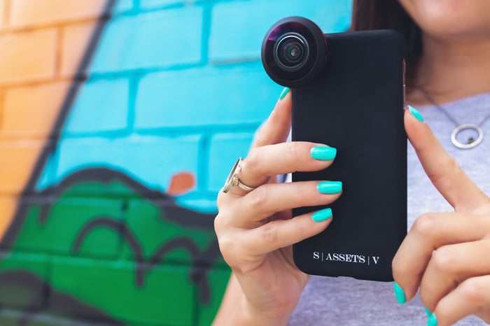 A person taking a photo with a phone that has an add-on-lens