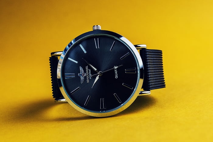 A watch photographed under studio lights against a yellow background