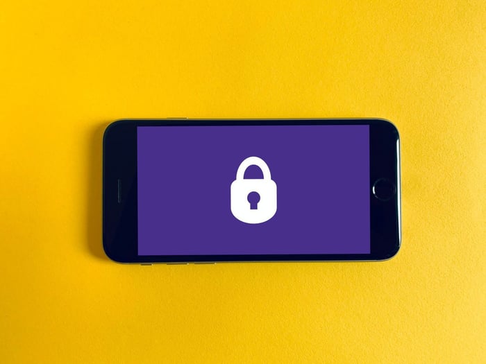 A phone with a padlock on the screen against a yellow background
