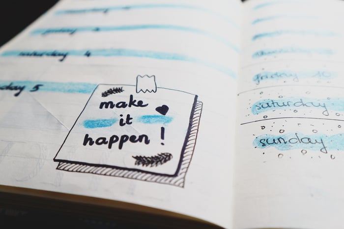 Een kalender met een post-it-notitie die zegt: make it happen