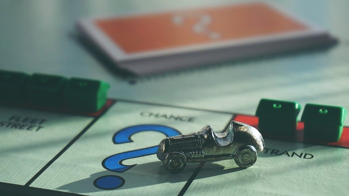 A Monopoly board with a card and houses next to a chance card slot