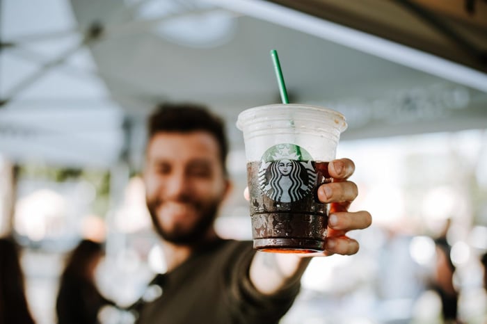 man holding clear starbucks cup up to the camera
