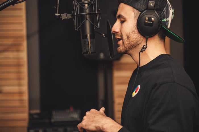 man wearing headphones speaking into studio microphone