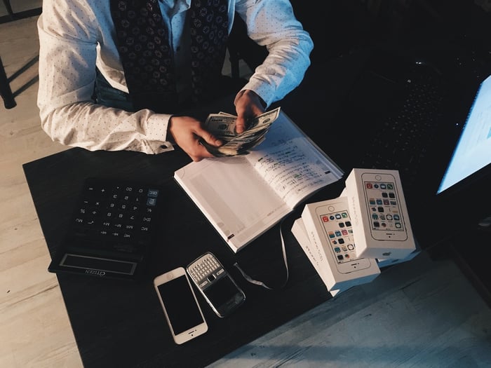 A person calculating accounts inside over a dark table 