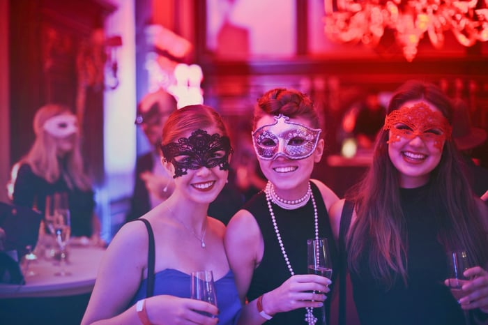 Women indoors at a party wearing masks
