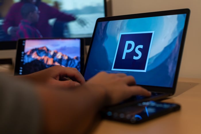 Một người tải Photoshop trên máy tính xách tay để chỉnh sửa ảnh