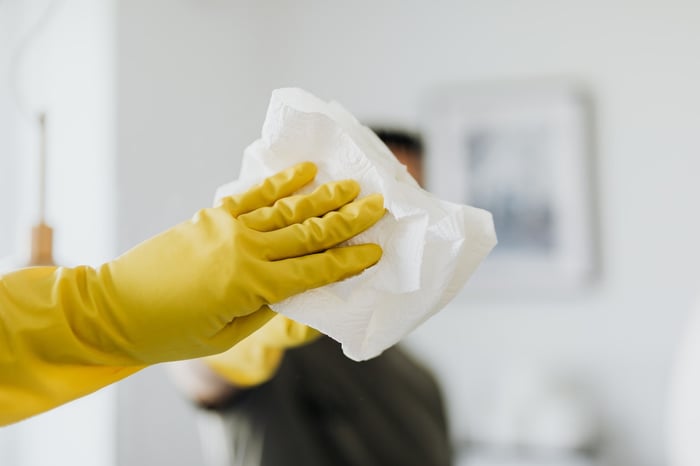 Persona che pulisce i vetri con dei guanti gialli