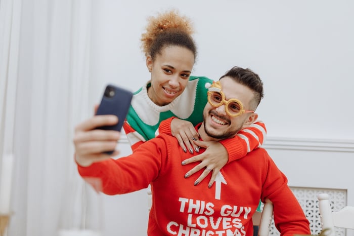 Two people in Christmas jumpers taking selfies 
