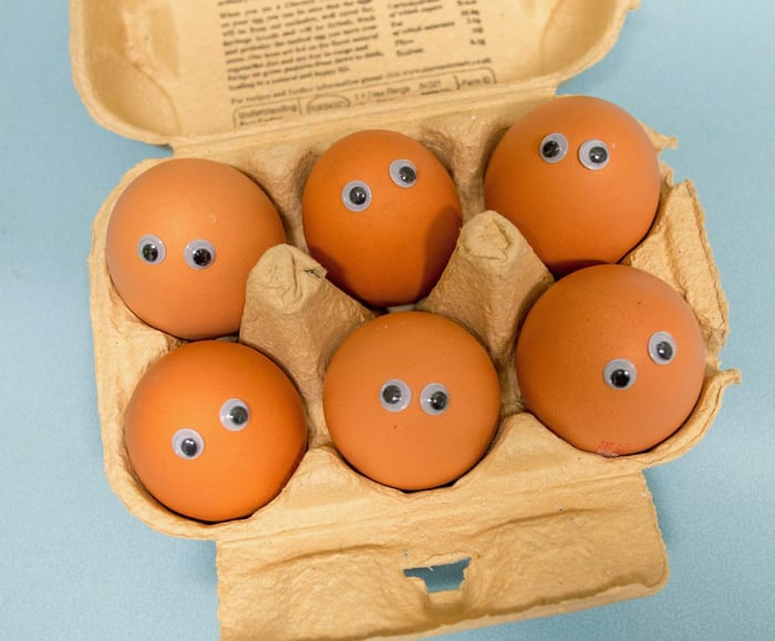 Jajka z oczami w pudełku na niebieskim tle