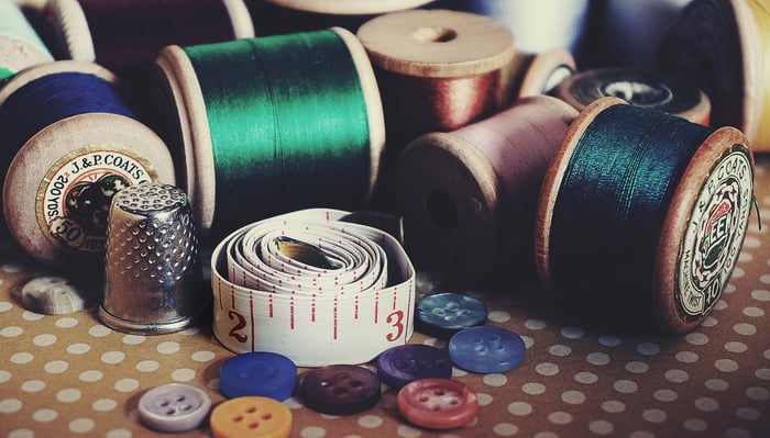 Thread, measuring tape, and other craft things on a table 