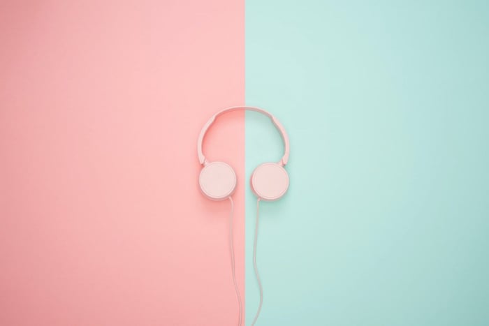 Pink headphones against a split mint and pink background