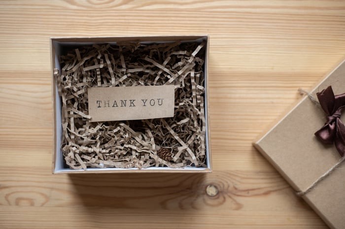 Piccola scatola marrone su un tavolo con  una nota di ringraziamento al suo interno