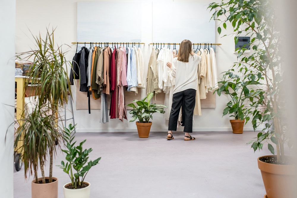 женщина смотрит на одежду на вешалках в магазине