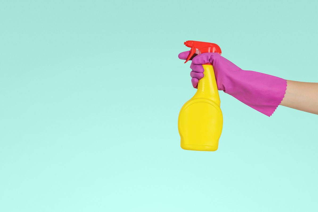 Een persoon die een gele fles met schoonmaakmiddel vasthoudt met een blauwe achtergrond