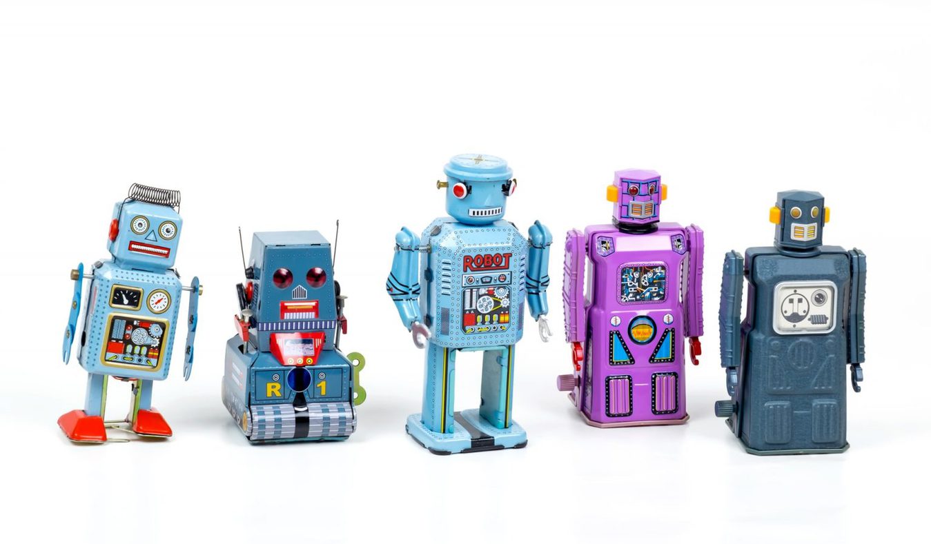 Little toy robots in a row against a white background