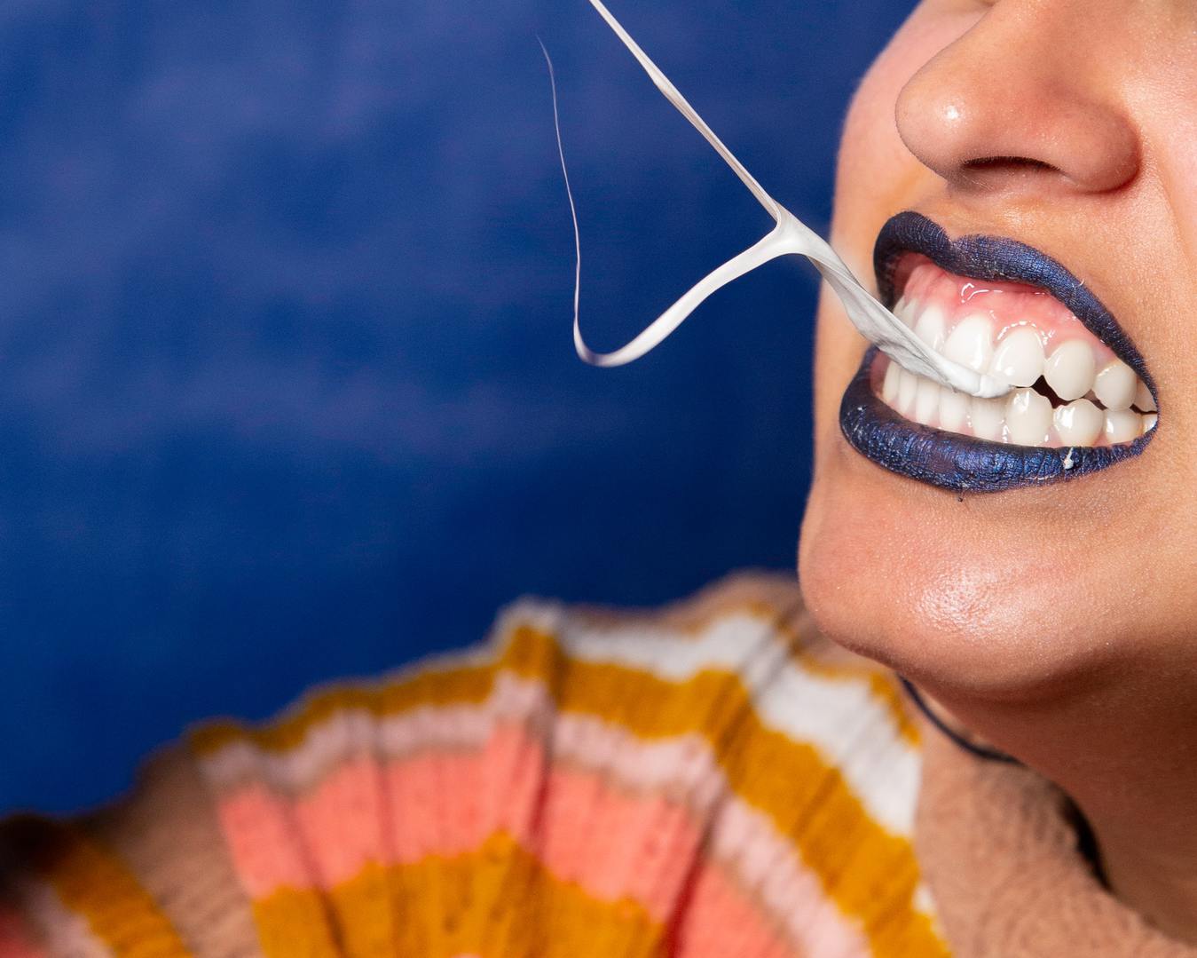 Donna con una gomma da masticare tra i denti e un rossetto blu