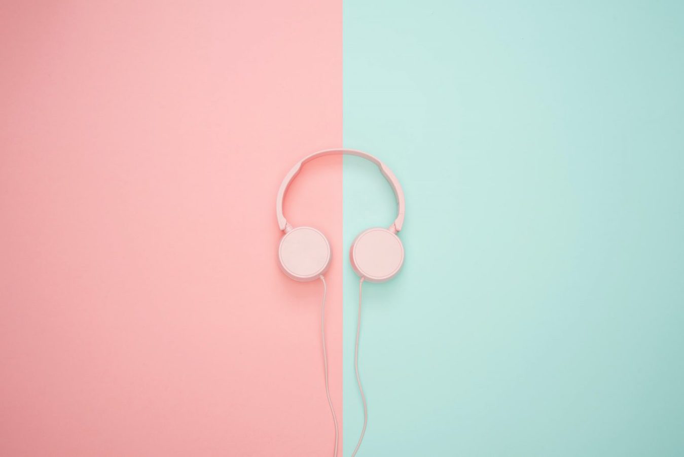 Pink headphones against a split mint and pink background